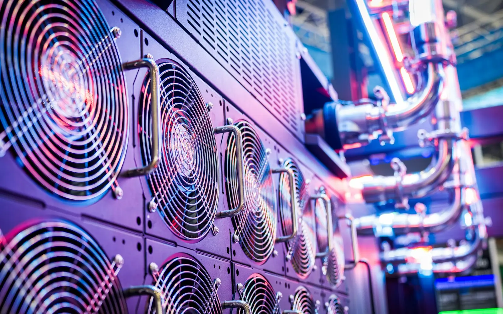 Close-up of server cooling fans and piping lit in blue and purple in a data center