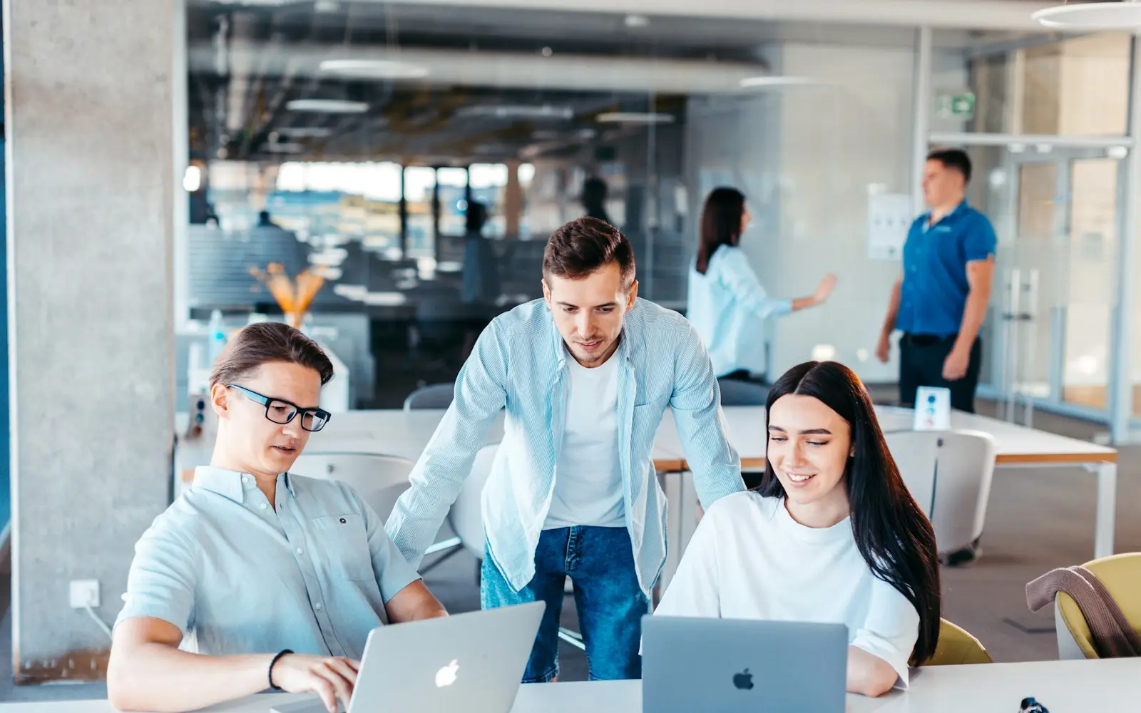 Colleagues reviewing work together on laptops at a shared desk in a modern office