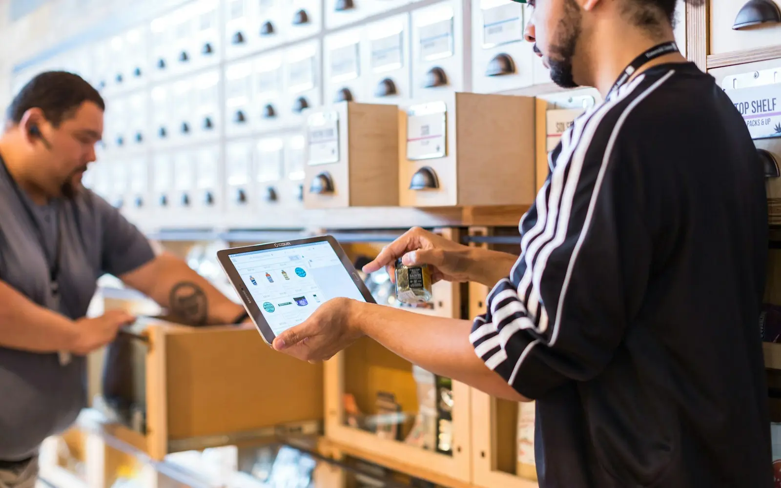 Two shop staff checking stock with a tablet in front of drawer cabinets