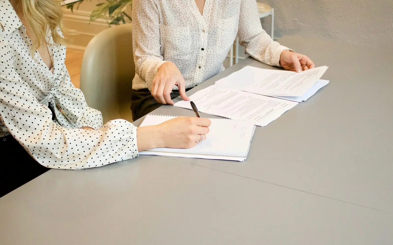Two people reviewing and signing documents at a grey table