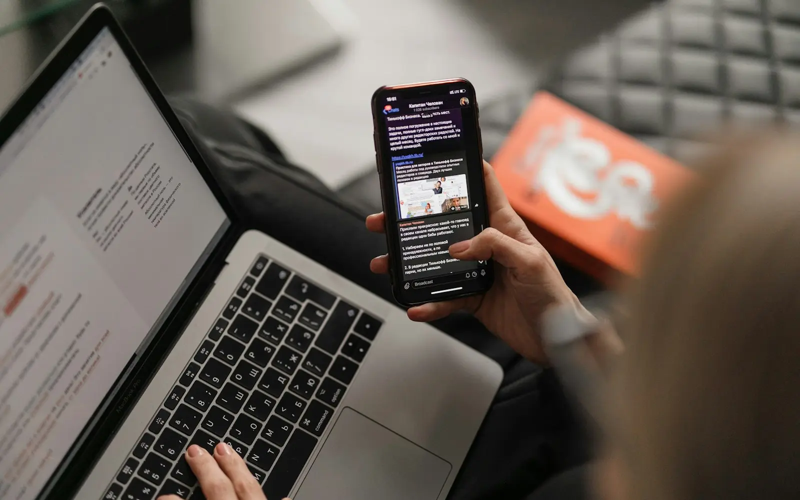 Person holding a smartphone above a laptop while testing an app