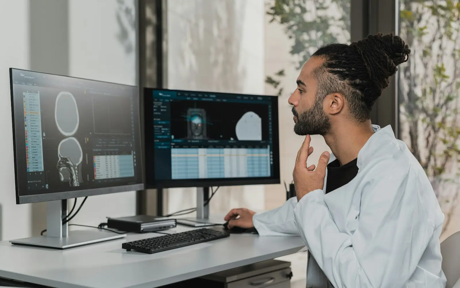 Analyst studying medical scan data on two desktop monitors