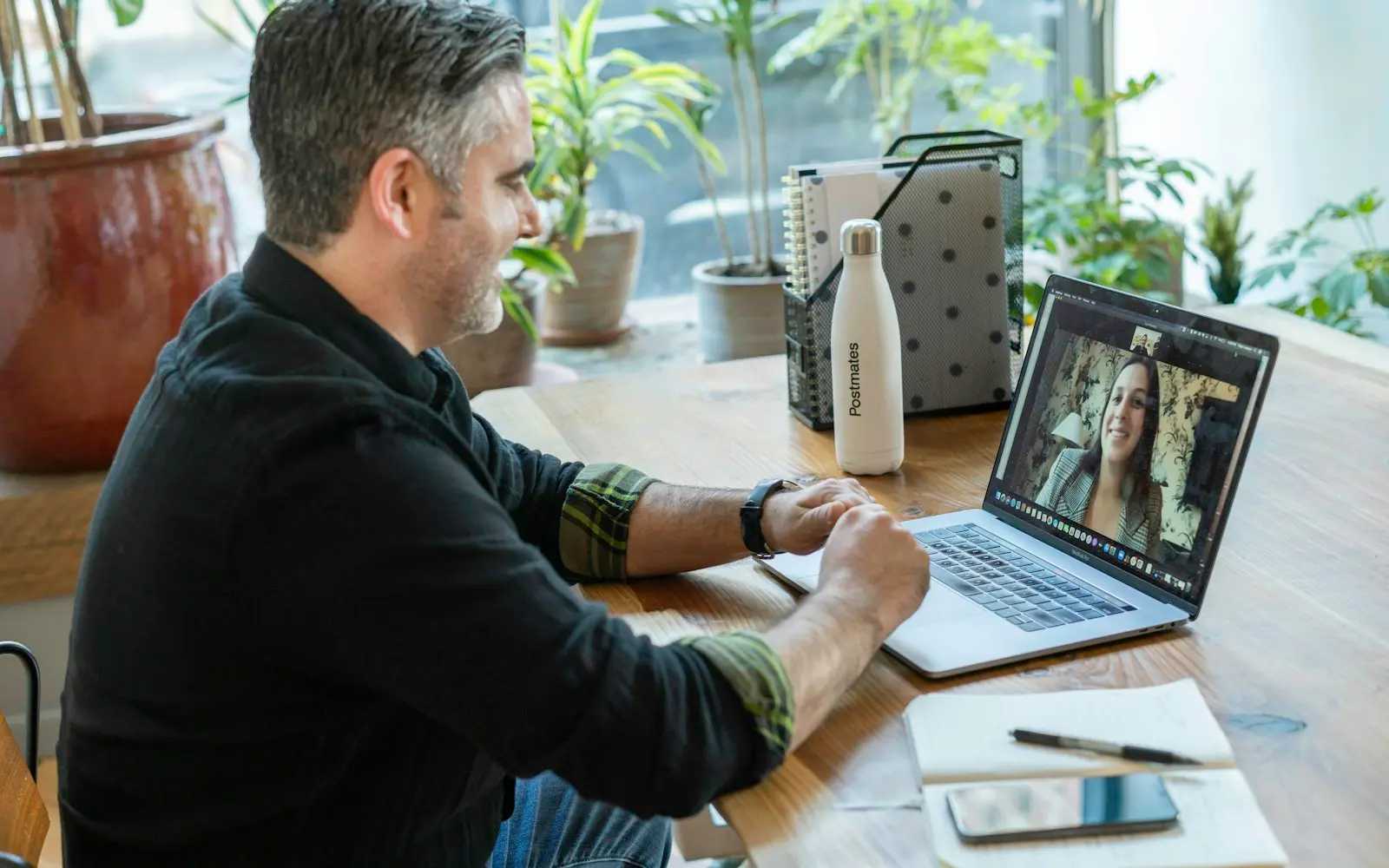 Man on a video call with a remote colleague at a wooden desk