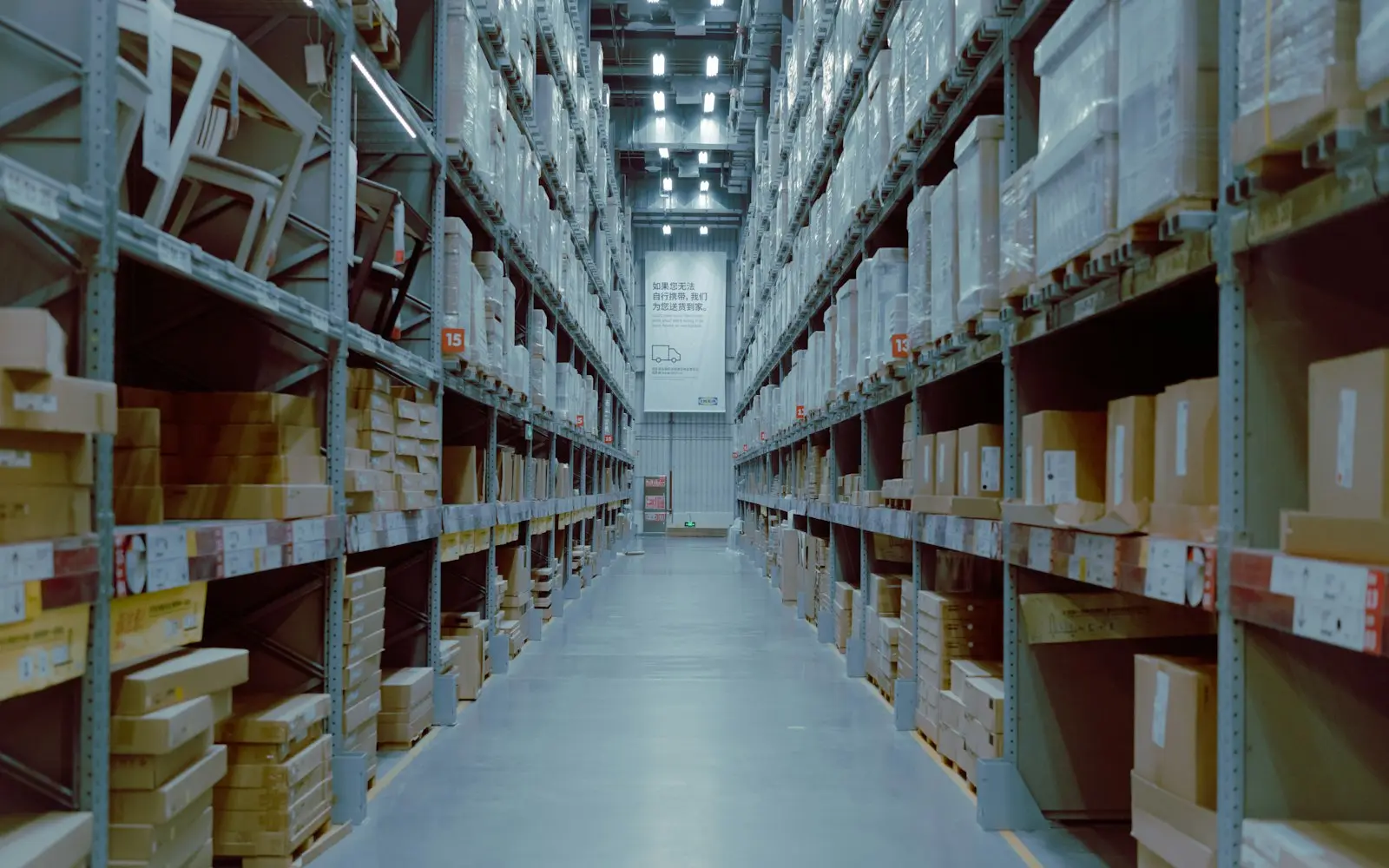 Warehouse aisle lined with tall shelves of boxed stock