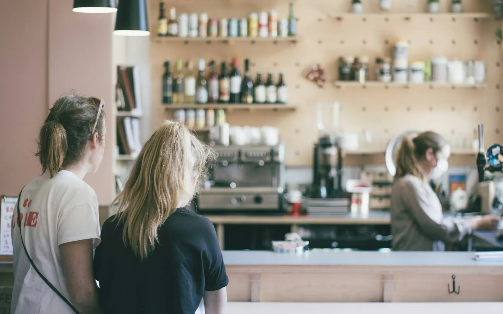 Customers ordering at a small cafe counter while the owner works behind it