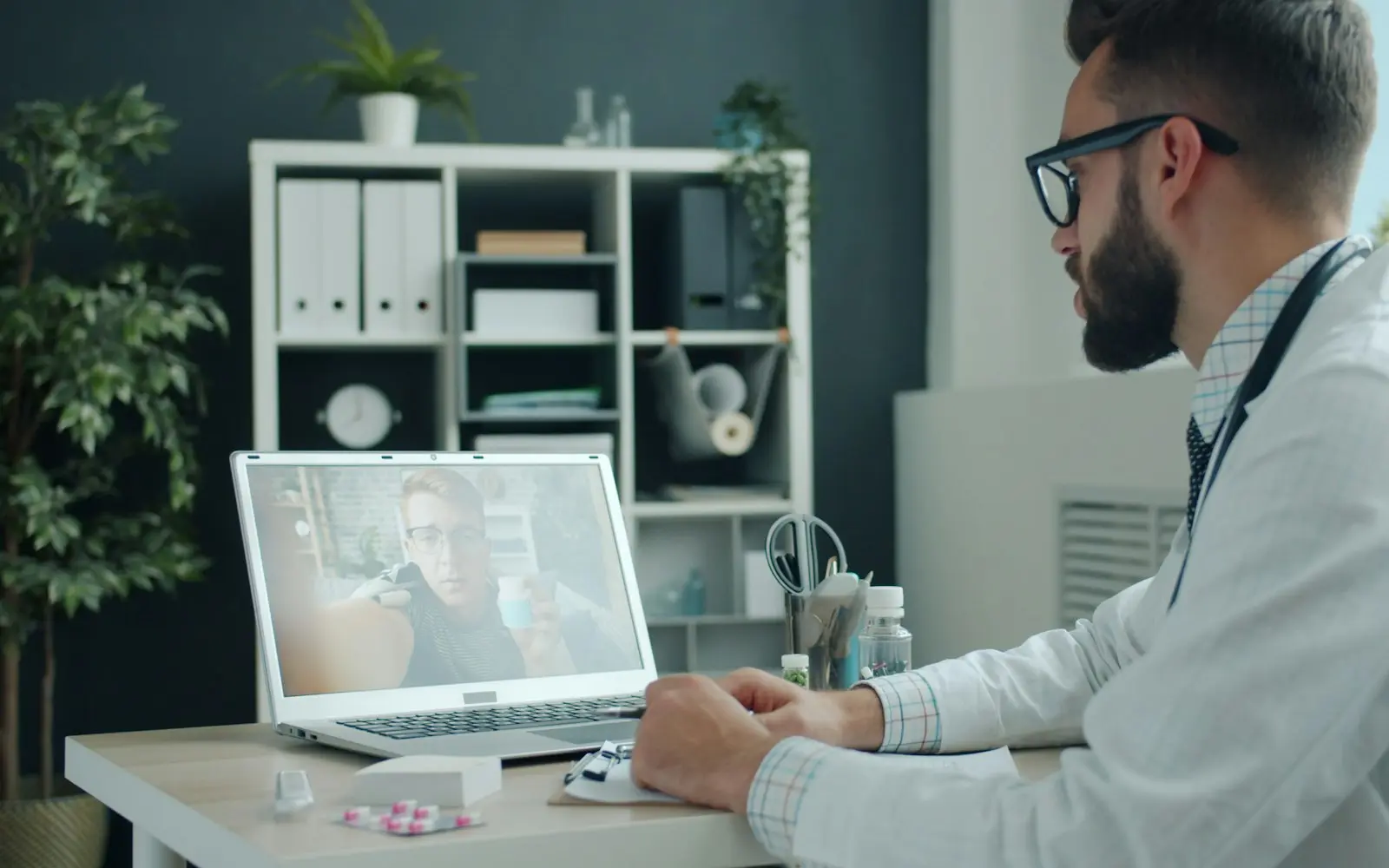 Bearded doctor with a stethoscope on a video consultation on a laptop